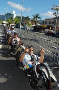 Atletas cadeirantes da Confederação Brasileira de Ciclismo andando de handbikes na rua.